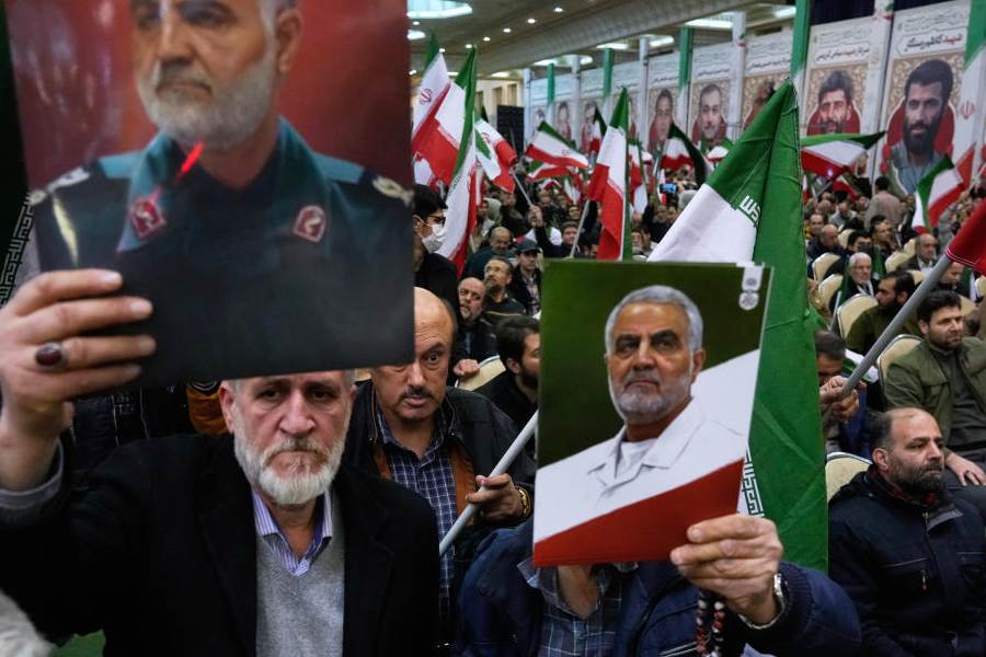 Two men hold up posters of the late commander of Iran's Revolutionary Guard expeditionary Quds Force, Gen. Qassem Soleimani, who was killed in a U.S. drone attack in 2020 in Iraq, during a ceremony commemorating his death anniversary at the Imam Khomeini grand mosque in Tehran, Iran, Thursday, Jan. 1, 2026.