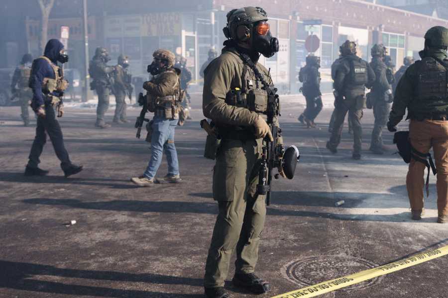 Federal agents stand amid teargas near the site where a man identified as Alex Pretti was fatally shot by federal agents trying to detain him, in Minneapolis, Minnesota