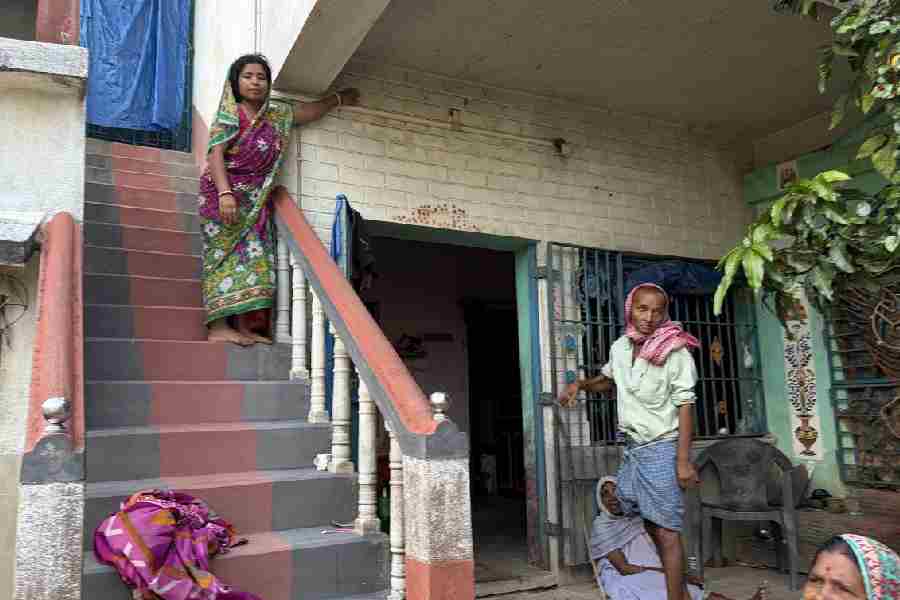 Mitali (standing) points to the level breached by the floods last year.