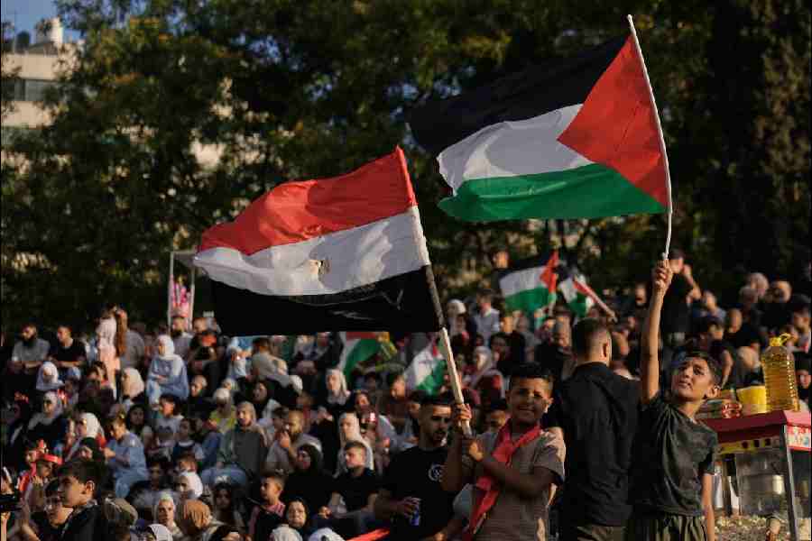 Youths wave Egyptian and Palestinian flags, right, as they watch a live broadcast of the World Cup round of 16 soccer match between Argentina and Egypt in the West Bank city of Nablus, Tuesday, July 7, 2026.