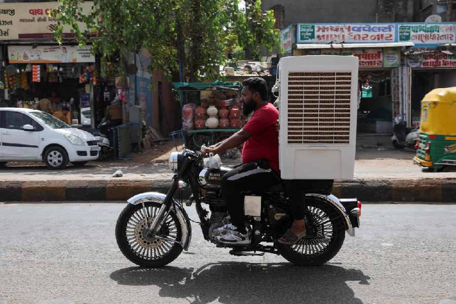 man transports an air cooler on a motorcycle during a heat wave in Ahmedabad, India, May 30, 2024.