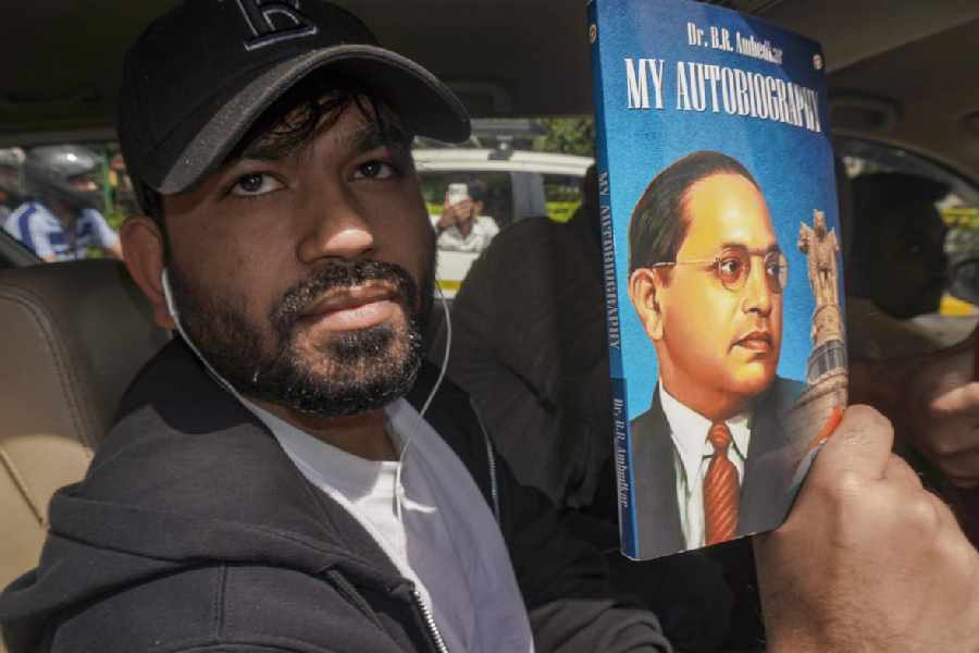 Cockroach Janta Party (CJP) founder Abhijeet Dipke shows a book of BR Ambedkar after his arrival at the airport, ahead of the protest at the Jantar Mantar to demand the resignation of Union Education Minister Dharmendra Pradhan over alleged examination-related lapses, in New Delhi, Saturday, June 6, 2026. 