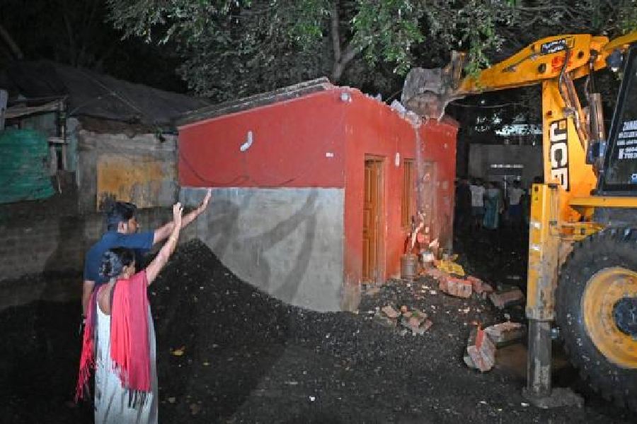 An earth mover demolishes a stall allegedly encroaching on railway land outside Jadavpur station early on Monday as some protesters try to resist.
