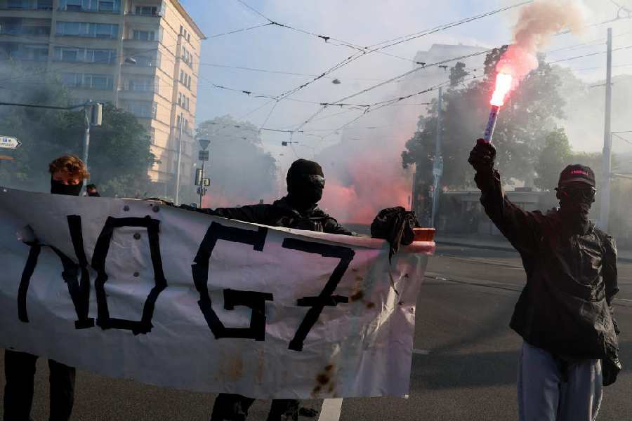 Demonstrators hold a banner and a flare, during a protest against the upcoming G7 summit in Evian-les-Bains in France, in Geneva, Switzerland, June 14, 2026.