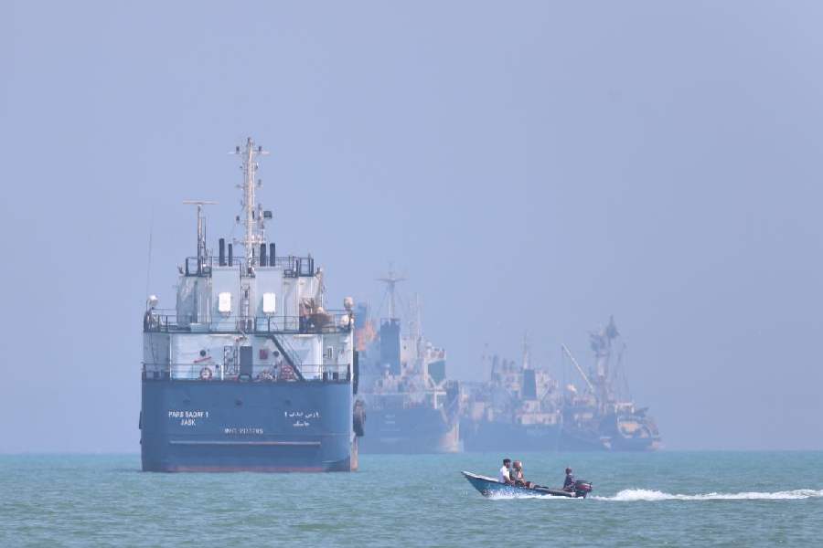 A small motorboat passes anchored vessels in the Strait of Hormuz off Bandar Abbas, Iran, Thursday, June 11, 2026.