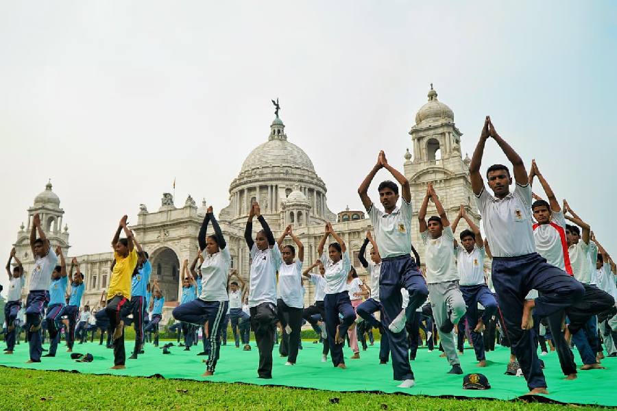 Students and sportspeople perform yoga at the Victoria Memorial grounds