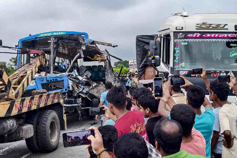 People look on as mangled remains of a bus are towed away after its collision with a truck on NH-27, at Ulladabri area, in Jalpaiguri district, West Bengal, Sunday, June 21, 2026.