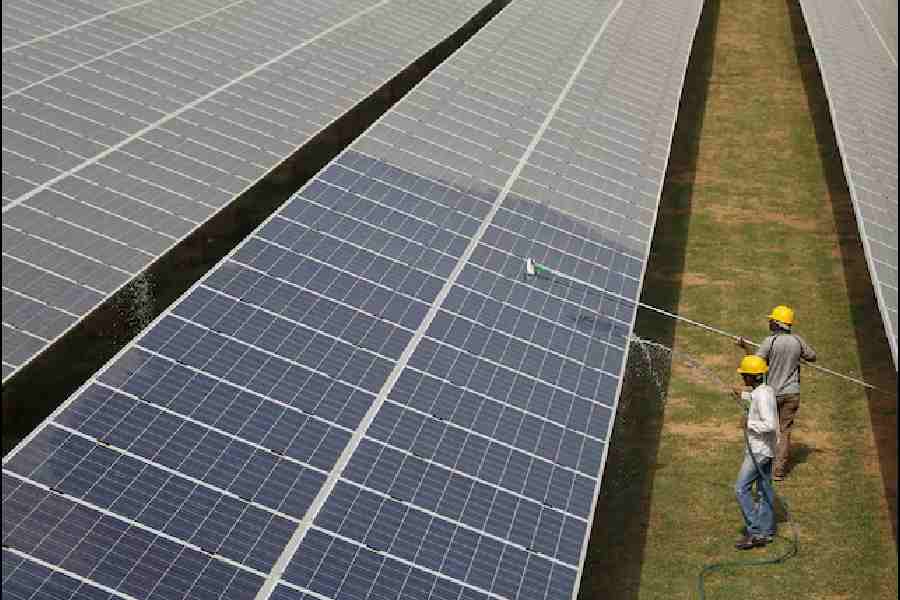 Workers clean photovoltaic panels inside a solar power plant in Gujarat, India, July 2, 2015.