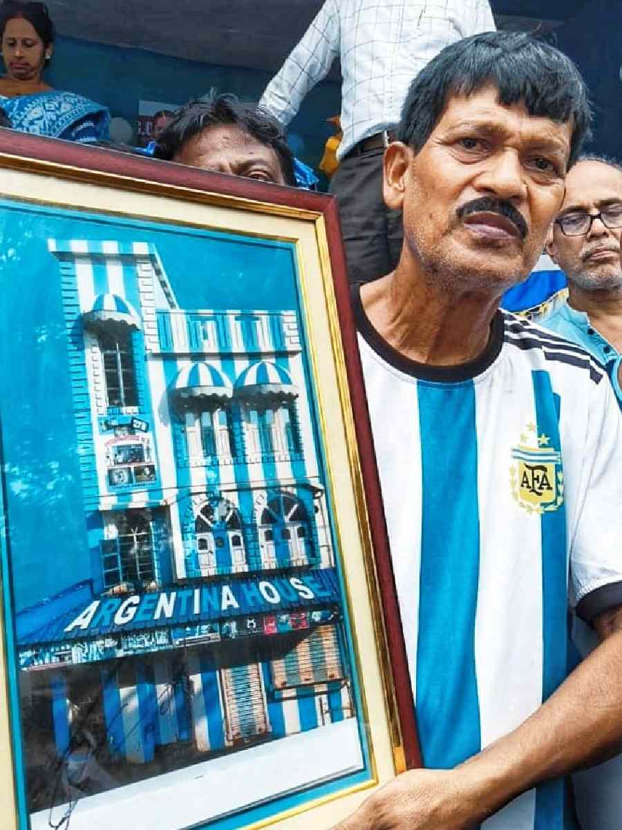 Shib Shankar Patra, a tea-seller, with a signed photograph from Messi. Patra has painted his house in the colours of the Argentine flag