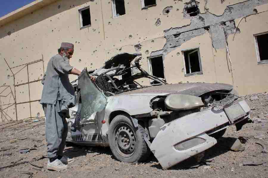 A man inspects a car damaged after a Pakistani strike in on a refugee camp in Takhta Pul district, Kandahar province, Afghanistan, Saturday, Feb. 28, 2026.
