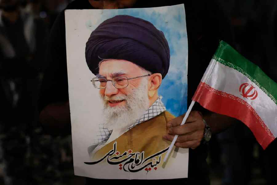 A Shiite Muslim supporter holds a portrait of Ayatollah Ali Khamenei and Irans's national flag, during a protes\t