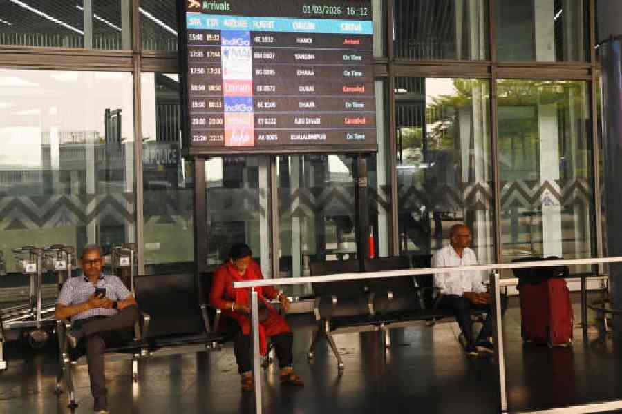 Passengers wait outside the Kolkata airport on Sunday afternoon