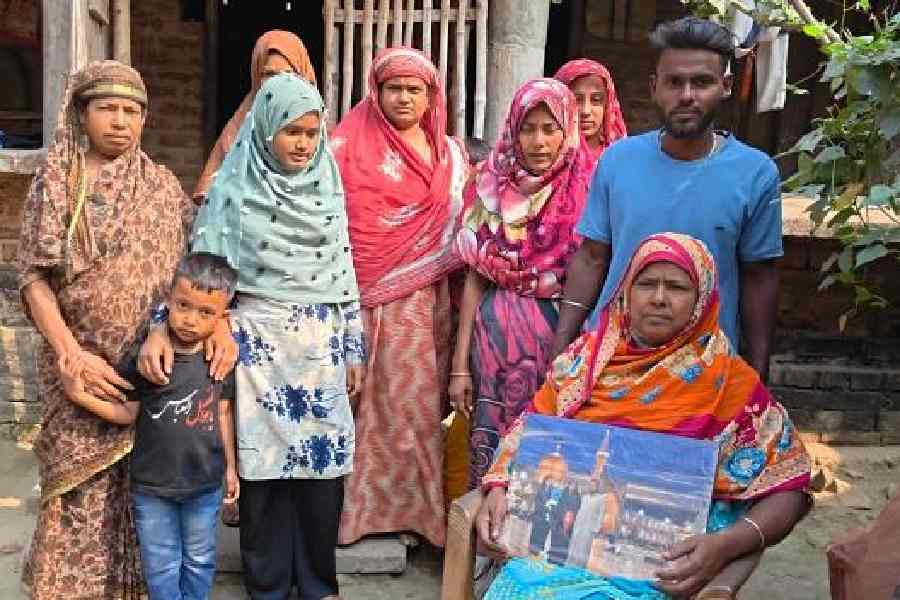 Yaar Banu, surrounded by her relatives, holds a photograph of her son Amir and his family at her home in Basirhat on Sunday afternoon. 