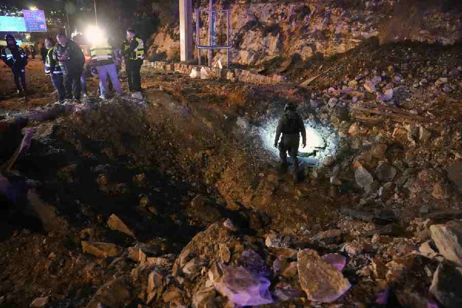 Israeli security forces inspect a damaged road after a missile launched from Iran struck Jerusalem, Sunday, March 1, 2026.