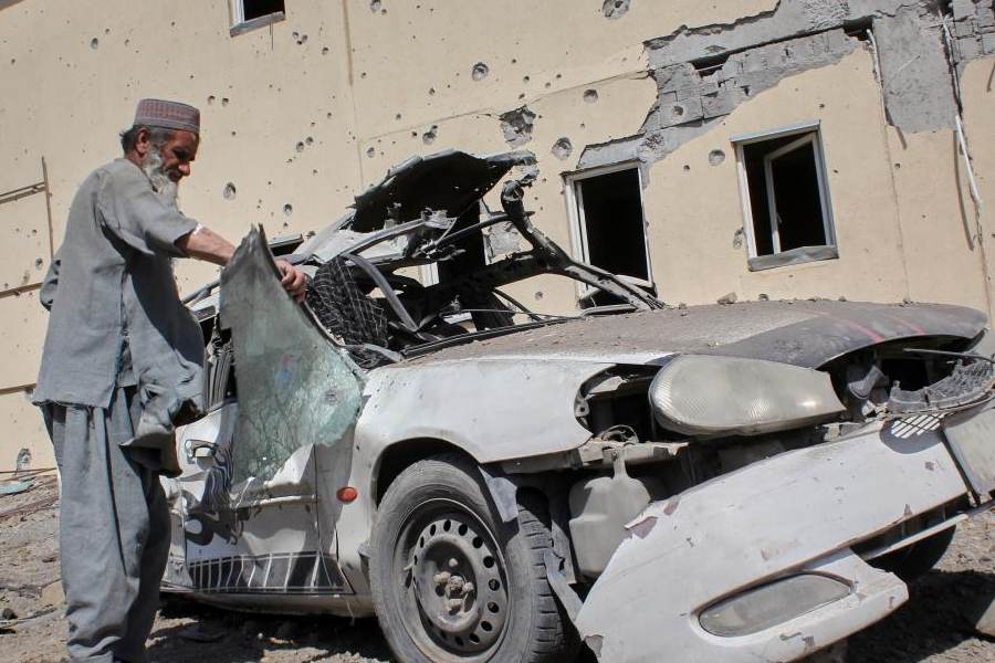A man inspects a car damaged after a Pakistani strike in on a refugee camp in Takhta Pul district, Kandahar province, Afghanistan, Saturday, Feb. 28, 2026.