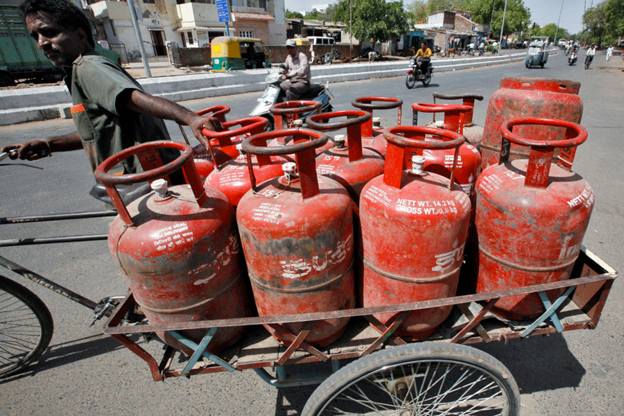 FILE PHOTO: A man pushes a trishaw loaded with cooking gas cylinders in the western Indian city of Ahmedabad, April 29, 2010.