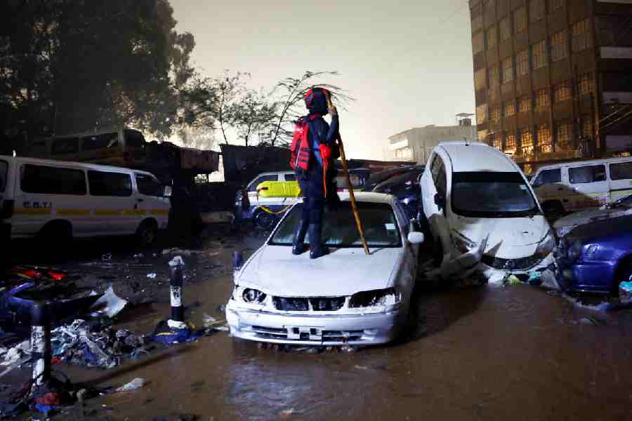 A member of the Kenya Red Cross stands atop a car in search of bodies trapped in the wreckages of vehicles destroyed following heavy rainfall in the Grogan area, popular for automotive workshops and secondhand spare parts in downtown Nairobi, Kenya, March 7, 2026.