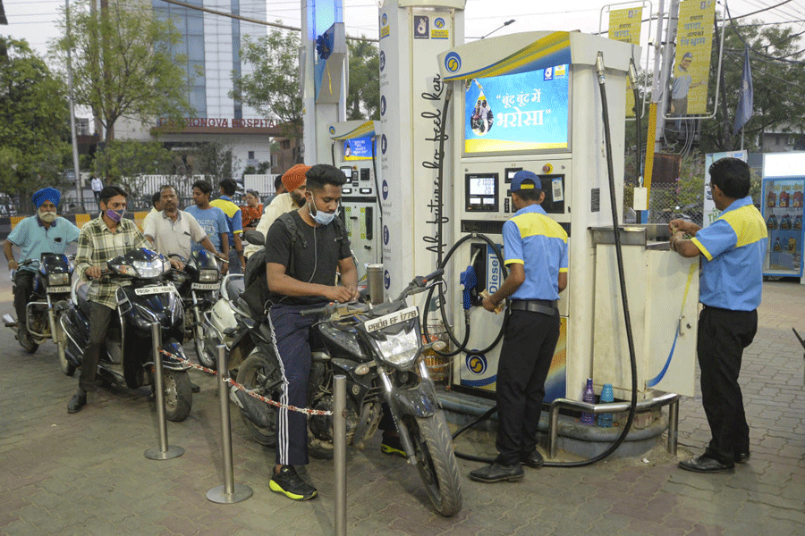 Petrol pump workers fill petrol in vehicles.