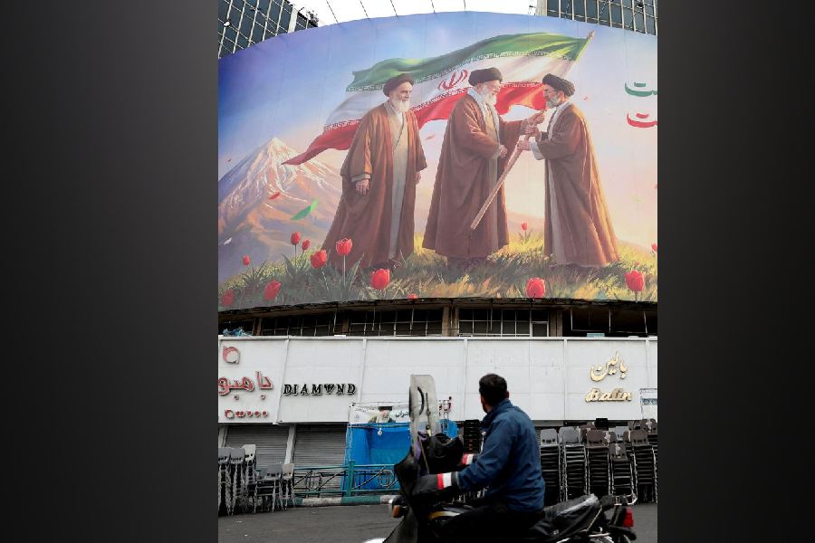 A man on a motorcycle looks at a large billboard featuring Iran's new Supreme Leader Mojtaba Khamenei, in Tehran, March 12, 2026