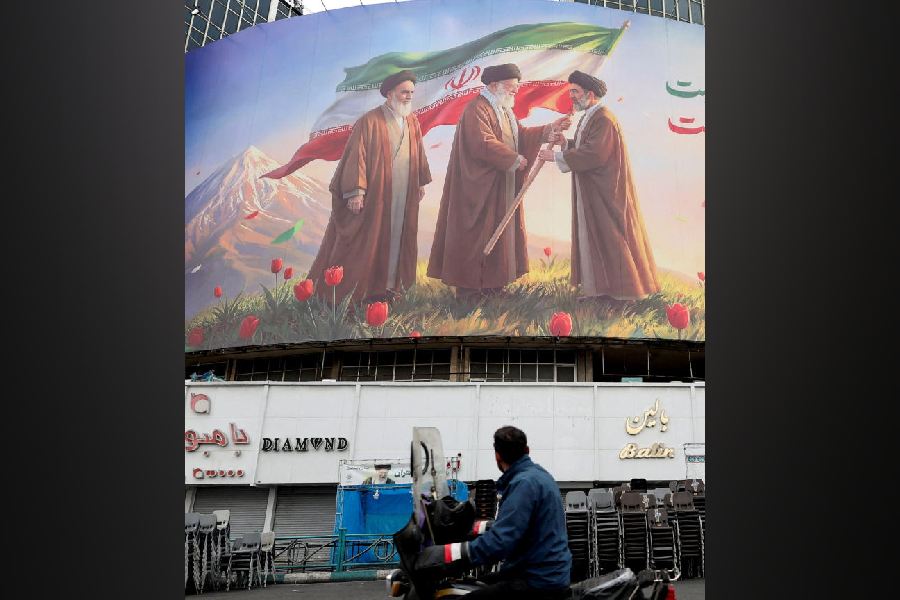 A man on a motorcycle looks at a large billboard featuring Iran's new Supreme Leader Mojtaba Khamenei, in Tehran, March 12, 2026