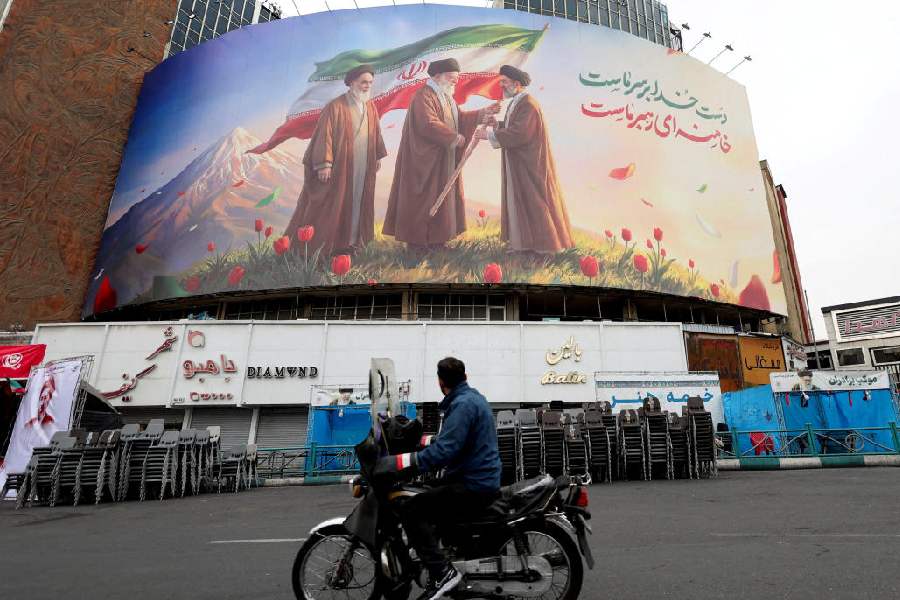A man on a motorcycle looks at a large billboard featuring Iran's new Supreme Leader Mojtaba Khamenei, in Tehran, March 12, 2026