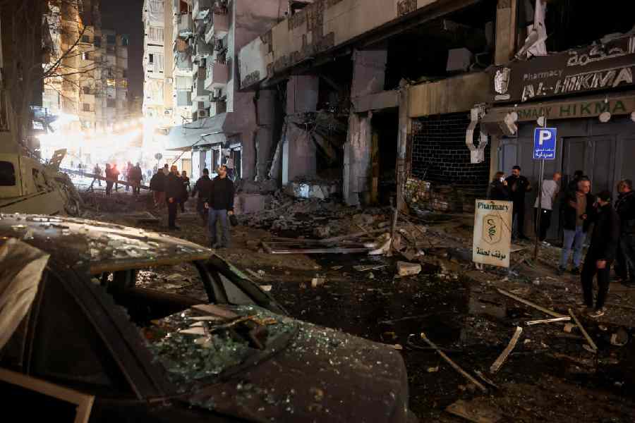 People stand amid rubble outside damaged buildings after an Israeli strike in the Zuqaq al-Blat district of Beirut, Lebanon, March 12, 2026.