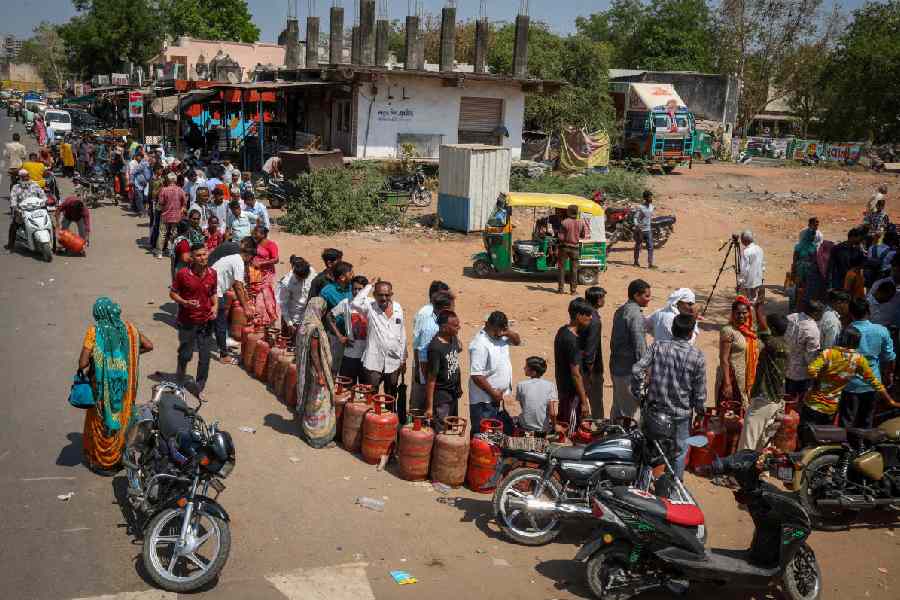 People queue with empty LPG cylinders outside gas agency in Ahmedabad, India