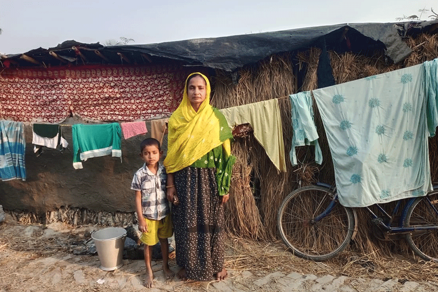 Mahima Molla with her youngest child in front of their hut in the Sundarbans.
