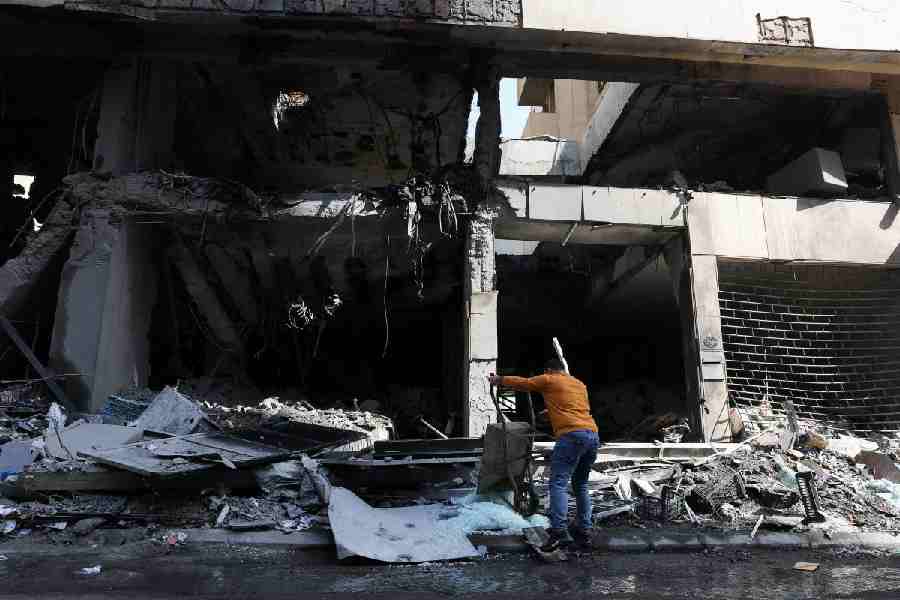 A man uses a wheelbarrow to dump broken glass, by a damaged building, in the aftermath of yesterday's Israeli strikes, following an escalation between Hezbollah and Israel amid the U.S.-Israeli conflict with Iran, in the Zuqaq al-Blat district in central Beirut, Lebanon, March 13, 2026.