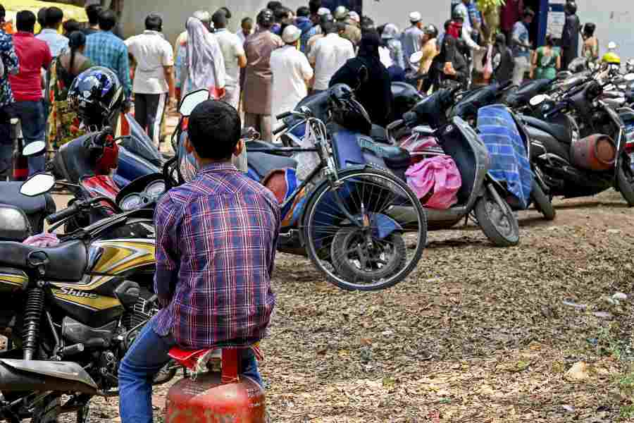 A boy sits on an empty LPG cylinder, outside a gas agency in Bengaluru, Friday, March 13, 2026