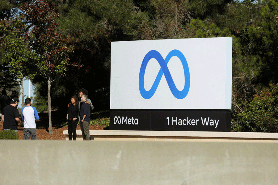 FILE PHOTO: People pose for a photo in front of Facebook\\\'s new rebrand logo Meta at its headquarters in Menlo Park
