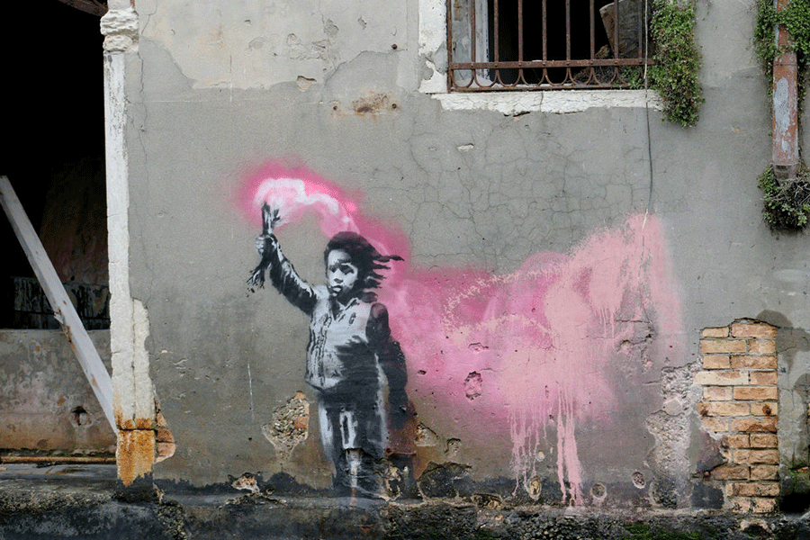 A mural depicting a migrant child wearing a lifejacket and holding a pink flare is seen along a canal in a Venice