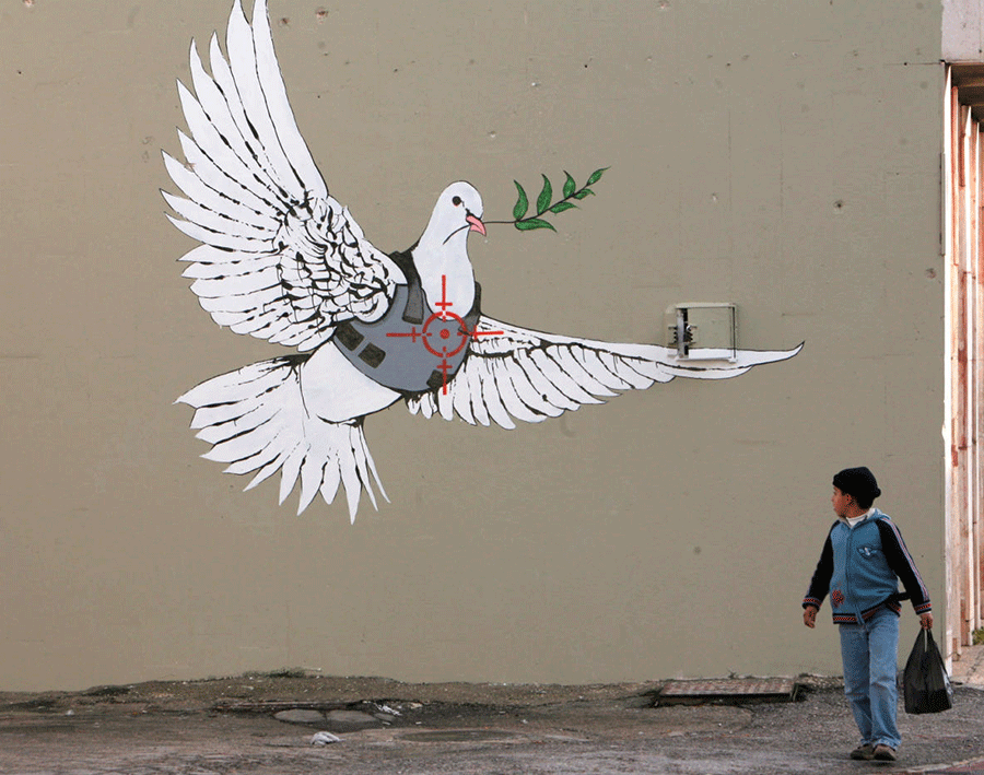 A Palestinian boy looks at one of six new images painted by British street artist Banksy as part of a Christmas exhibition in the West Bank town of Bethlehem