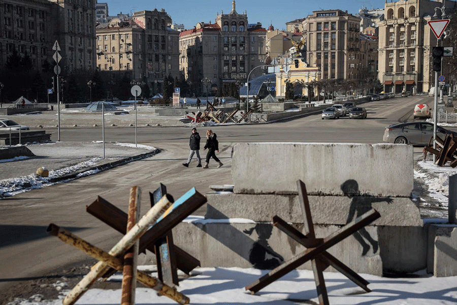 People walk down a street near anti-tank constructions in central Kyiv