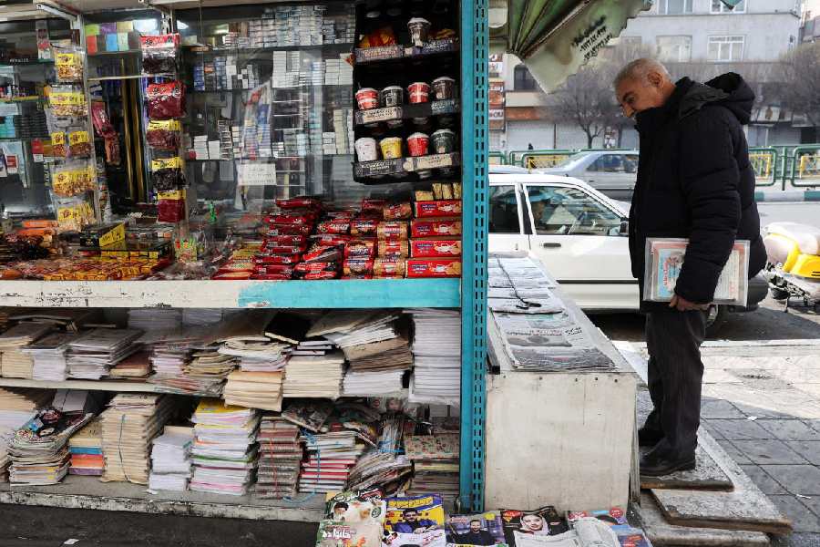 A man looks at newspapers for sale at a shop, amid the U.S.-Israeli conflict with Iran, in Tehran, Iran, March 14, 2026