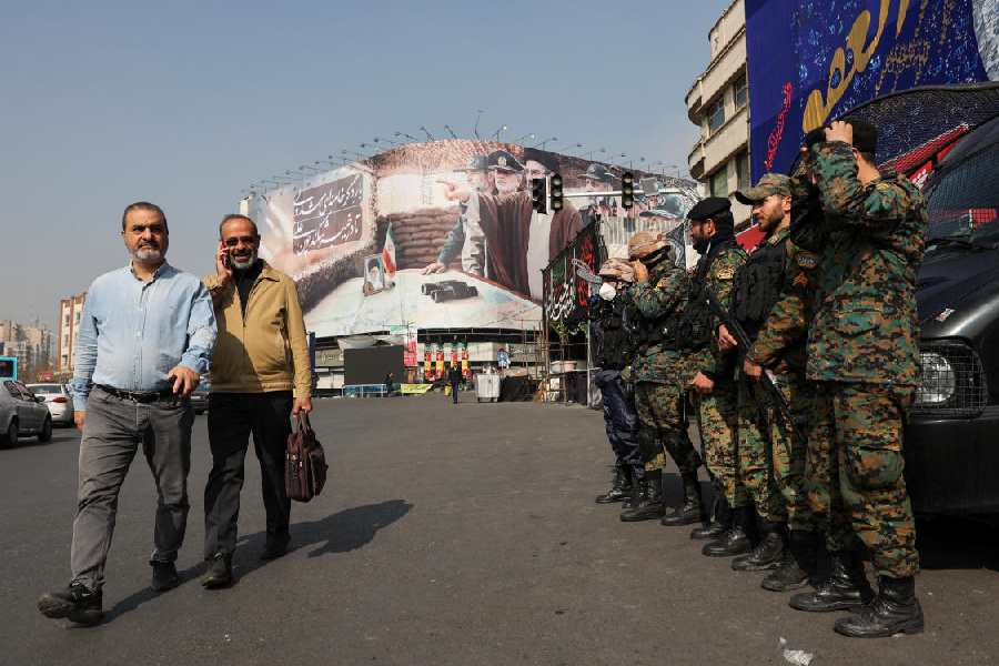 People walk past police personnel on guard near a banner featuring Iran's new Supreme Leader Mojtaba Khamenei, Tehran, Iran March 14, 2026.