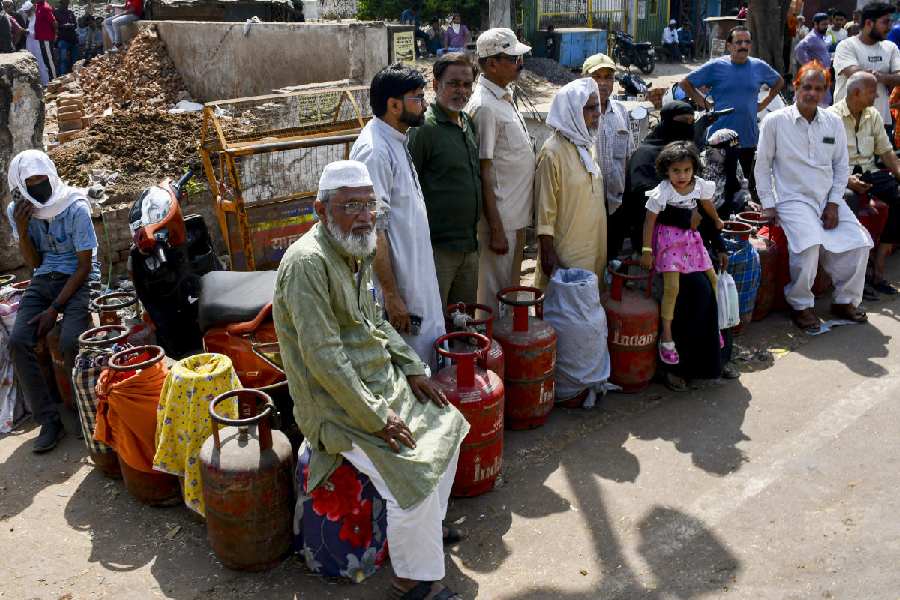 People wait in a queue with empty LPG cooking gas cylinders