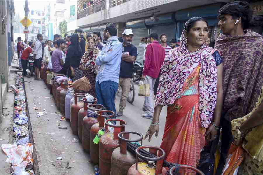 People wait in a queue with empty LPG cooking gas cylinders amid a shortage linked to the ongoing West Asia conflict affecting the global energy supply chain, in Noida, Tuesday, March 17, 2026.