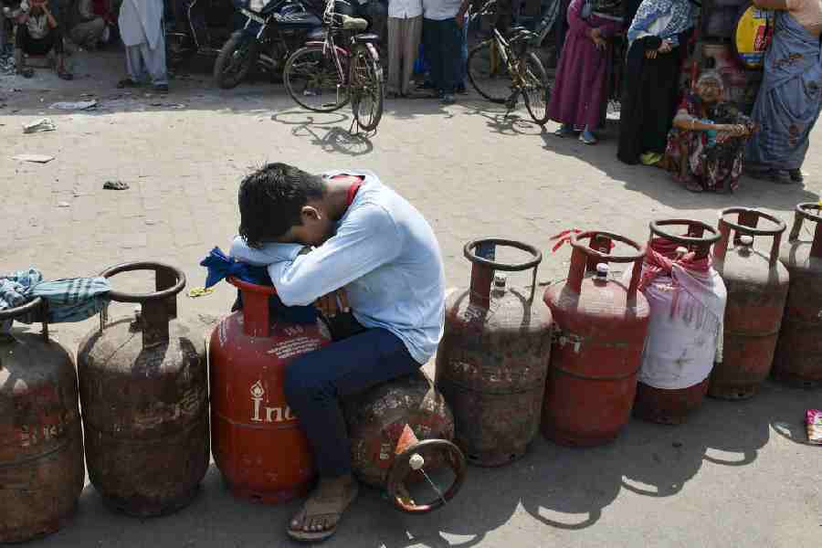 A child sits over an empty LPG cooking gas cylinder, as people arrive to avail refilled ones, amid a shortage linked to the ongoing West Asia conflict affecting the global energy supply chain, in Prayagraj, Tuesday, March 17, 2026.