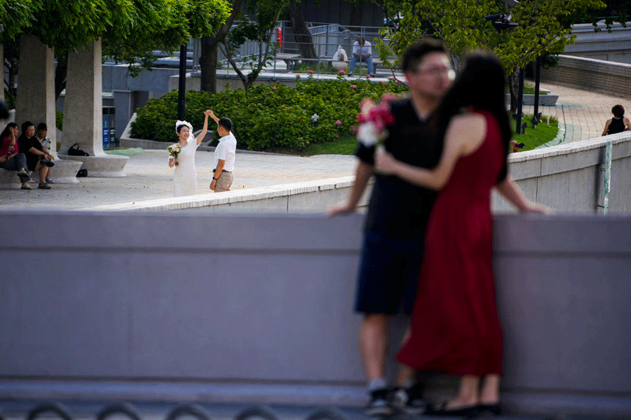 Couples prepare to get their photo taken during a wedding photography shoot on a street, in Shanghai