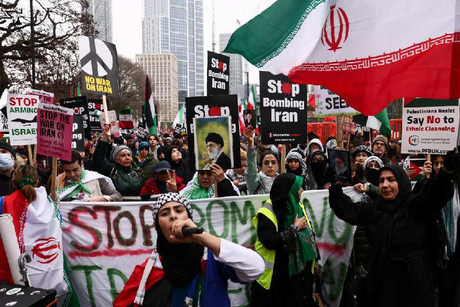 Anti-war activists hold signs, images of Iran's late Supreme Leader Ayatollah Ali Khamenei, and Iranian flags as they gather outside the US embassy, in London, Britain, March 7.