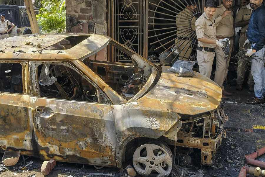 Police personnel gather near the wreckage of a car after a fire broke out in a house, in Indore, Madhya Pradesh, Wednesday, March 18, 2026. Seven persons were killed in the incident.