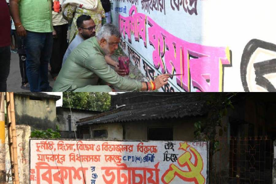 Debasish Kumar, Trinamool candidate from Rashbehari constituency, paints a wall on Thursday; (below) CPM graffiti in Jadavpur.