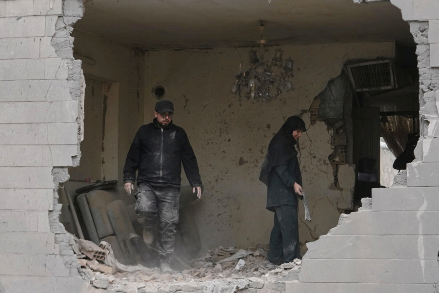People clean debris from their apartment in Tehran, Iran, Sunday, March 15, 2026, damaged when a nearby police station was hit in a U.S.-Israeli strike on Friday.