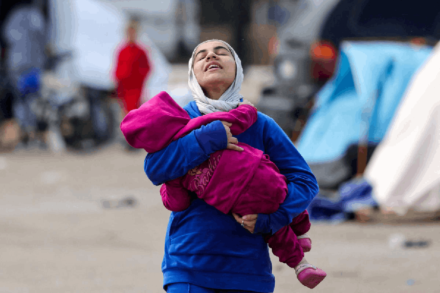 A woman carries a child near shelters of displaced people on the day Muslim worshippers attend Eid al-Fitr prayers to mark the end of the holy fasting month of Ramadan, following an escalation between Hezbollah and Israel amid the U.S.-Israeli conflict with Iran, in Beirut, Lebanon, March 20, 2026. 