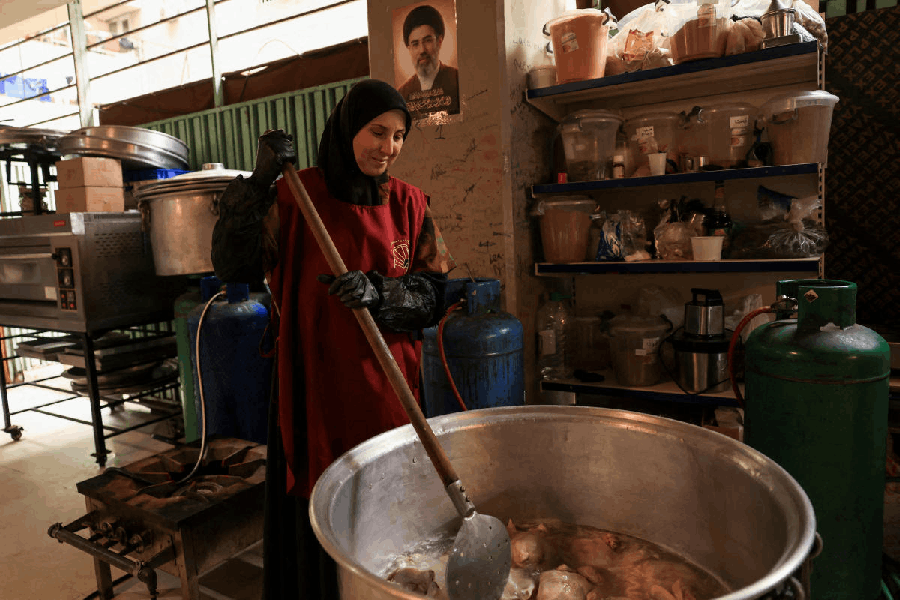 A woman cooks food on the day of Eid Al-Fitr, next to a placard with an image of Iran's new Supreme Leader, Mojtaba Khamenei, at a school which is hosting displaced people, following an escalation between Hezbollah and Israel, amid the U.S.-Israeli conflict with Iran, in Beirut, Lebanon, March 20, 2026. 