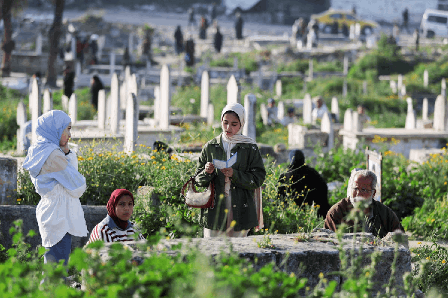 Palestinians visit a grave at a cemetery on Eid al-Fitr, which marks the end of the Muslim holy fasting month of Ramadan, in Gaza City, March 20, 2026. 