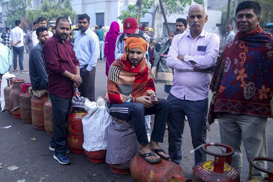 People wait in a queue with empty LPG cooking gas cylinders to avail refilled ones, in Noida, Saturday, March 21, 2026.