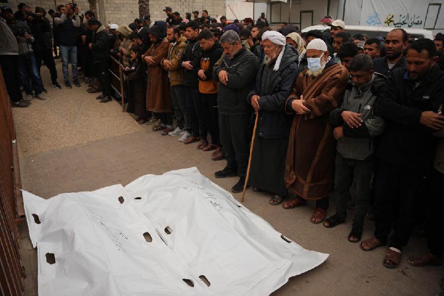Mourners pray over the bodies of two Palestinian policemen killed in an Israeli military strike, during their funeral at Nasser Hospital in Khan Younis, Gaza Strip