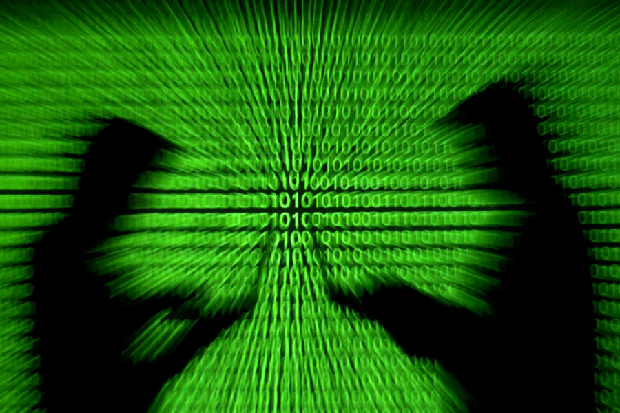 Silhouettes of laptop users and a projection of binary code are seen in this picture illustration
